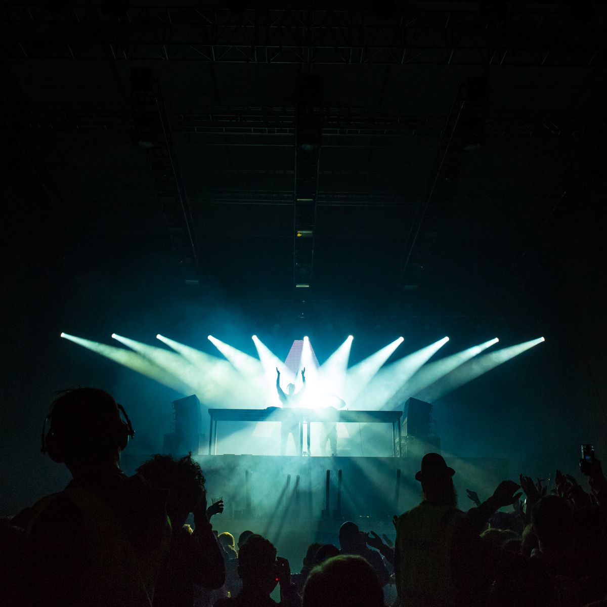 Foule dense debout devant un DJ lors d'un concert éclairé de lumières vibrantes