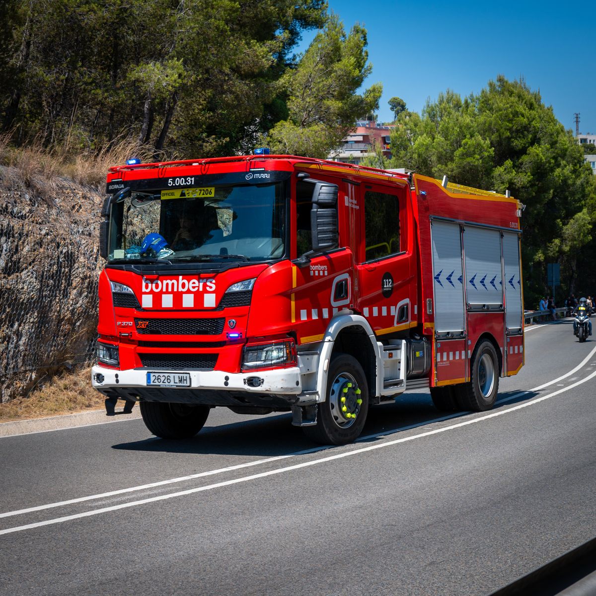 Camion de secours rouge circulant sur une route ensoleillée pour une intervention d'urgence